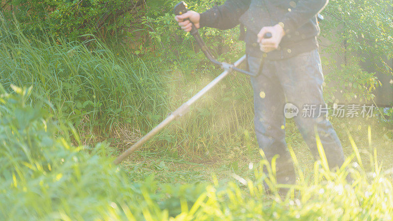 Man MOWS grass with trimmer, focus on前景模糊的背景